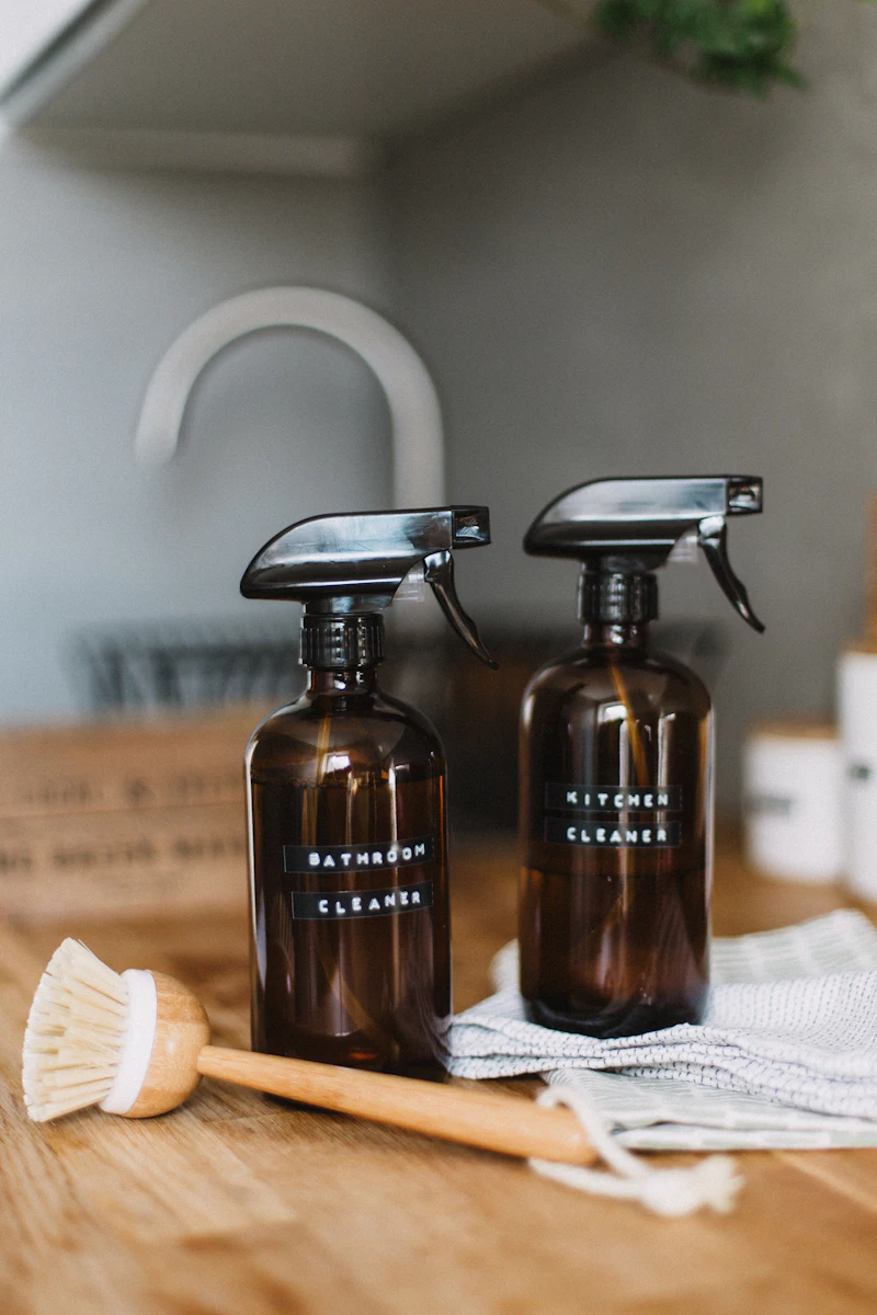 Two amber refill bottles of our own cleaning spray beside a dish brush