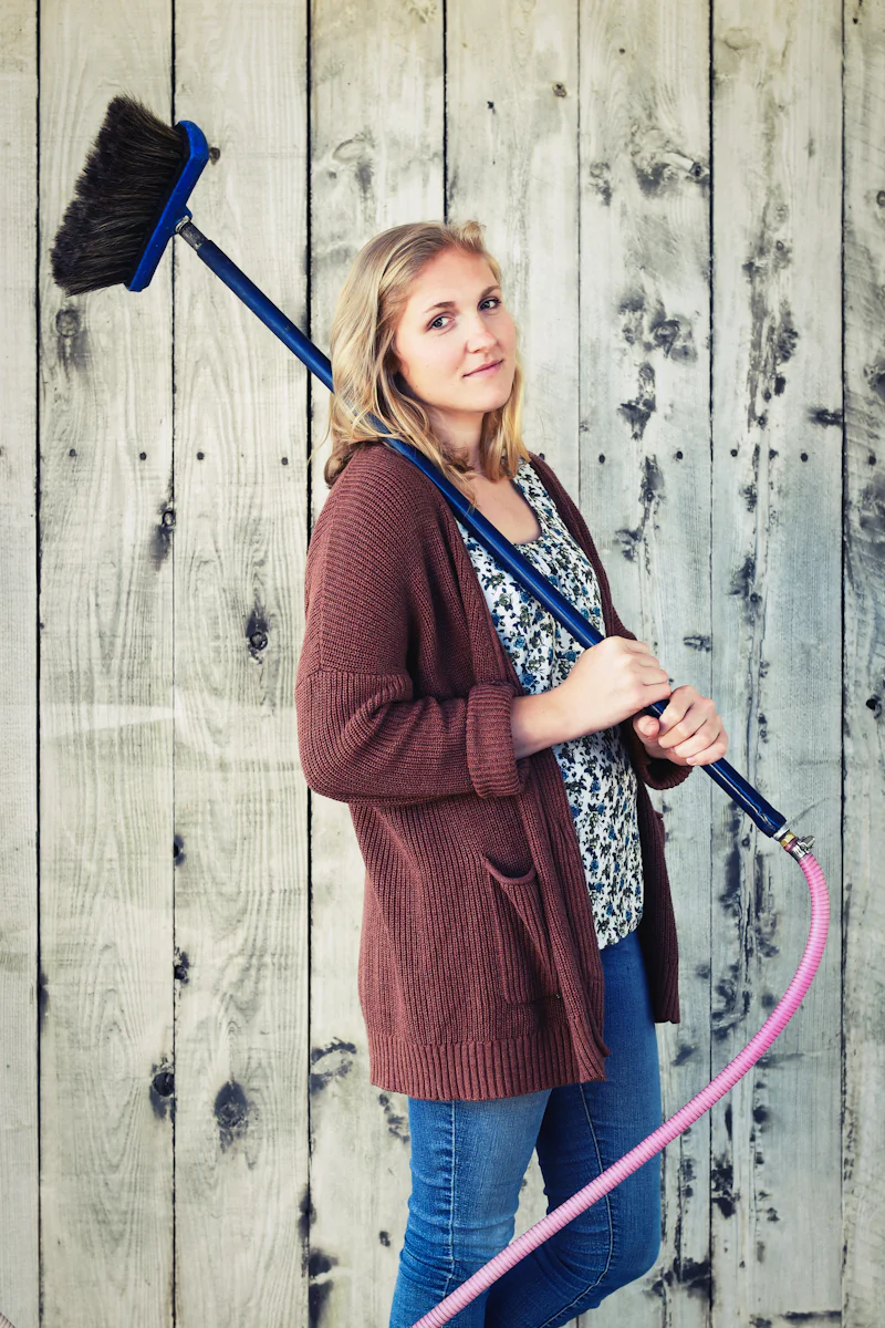 Shona holding a long-handled brush and smiling